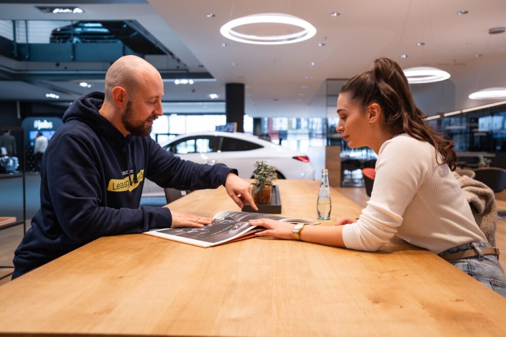 Mann und Frau sitzen an einem Tisch im Autohaus