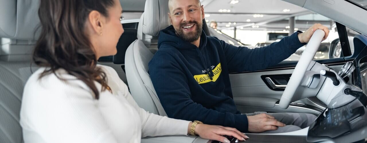 Frau und Mann sitzen lachend im Auto