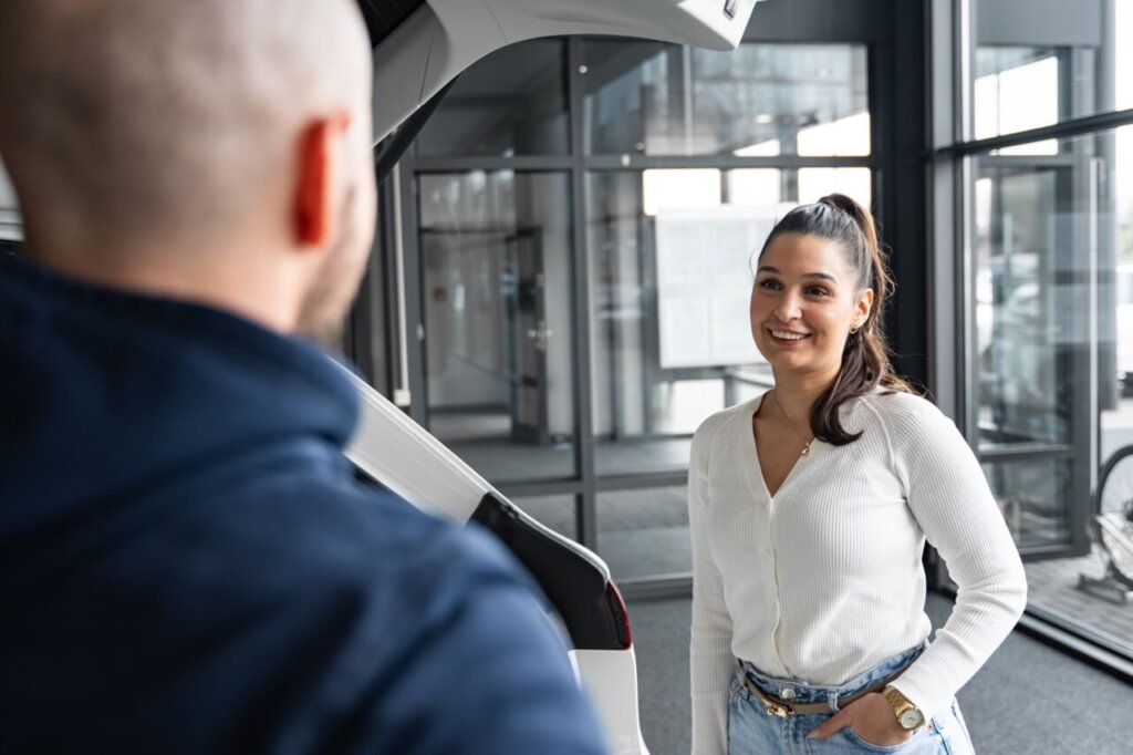 Mann und Frau stehen sich in Autohaus gegenüber