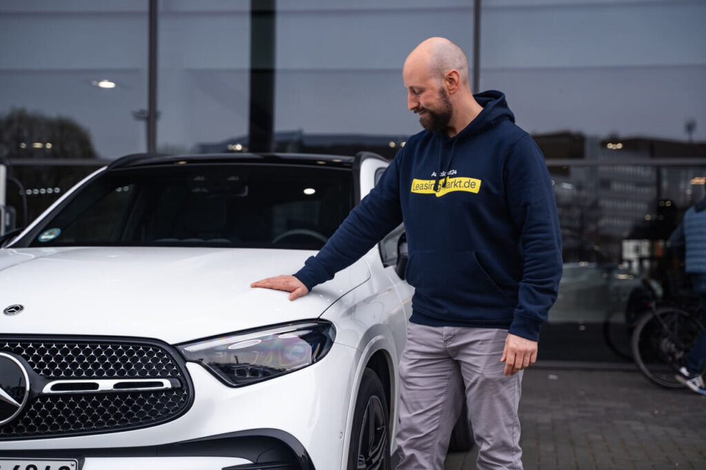 Mann legt Hand auf Motorhaube eines Autos